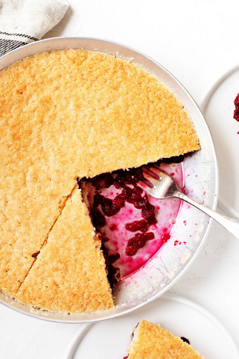 A pie dish full of cake with a cranberry and walnut bottom.