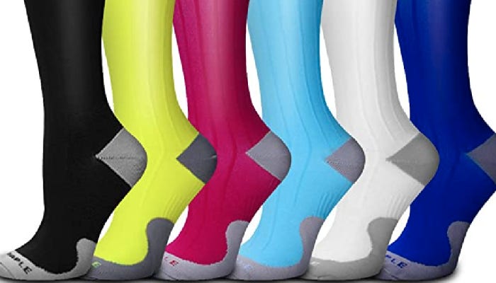 Six compression socks are shown against a white background. From left to right, the socks are black, yellow, red, light blue, white, and dark blue. Each sock has grey toes and heels.