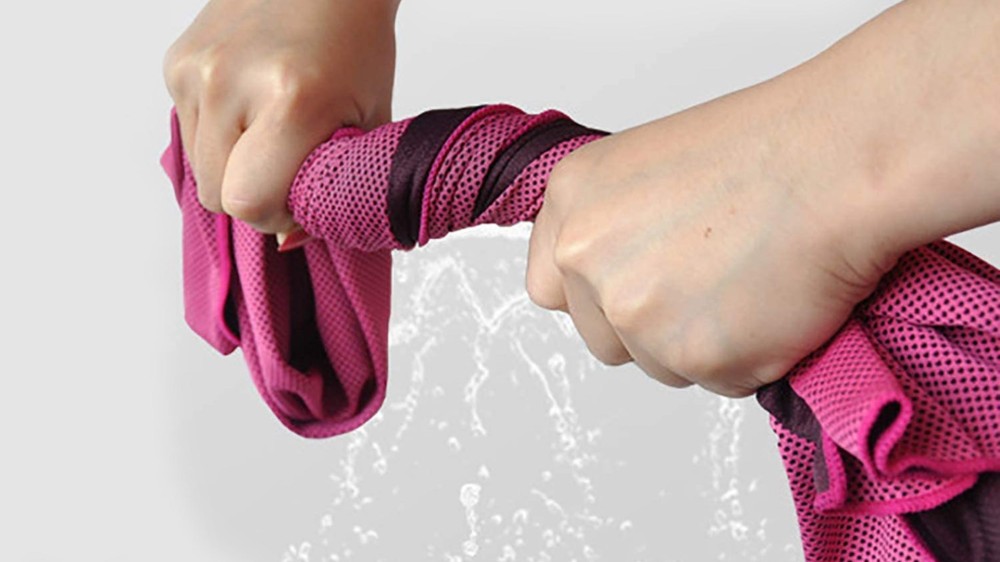 A person twists a pink towel to squeeze out water.