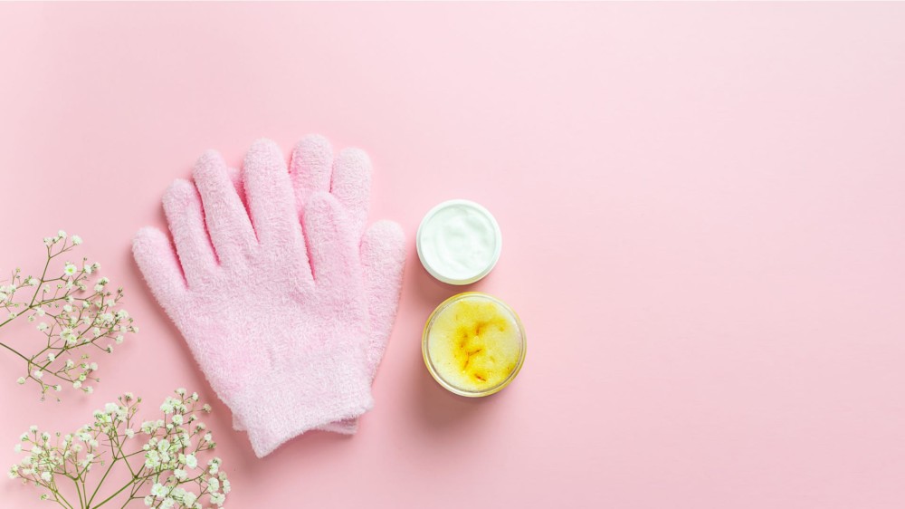 two exfoliating gloves next to body products.