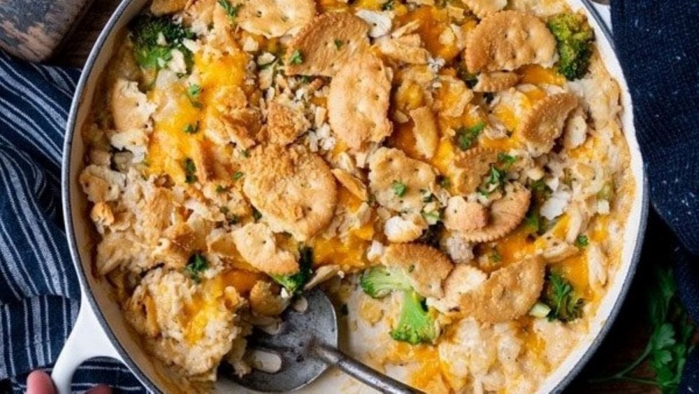 A casserole dish full of chicken broccoli and rice casserole topped with crumbled Ritz crackers.