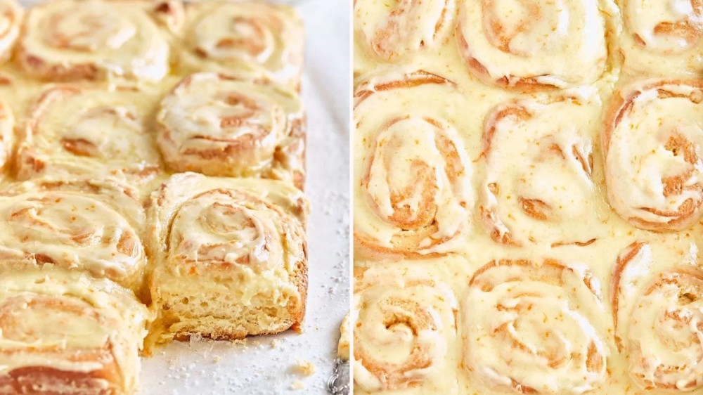 A tray of orange rolls with the corner roll pulled out; overhead view of frosted orange rolls