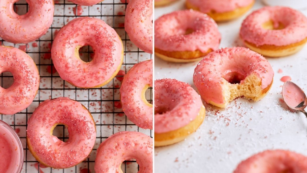 A tray of doughnuts with an orange glaze; a doughnut with a bite taken out and a spoon of pink frosting next to it