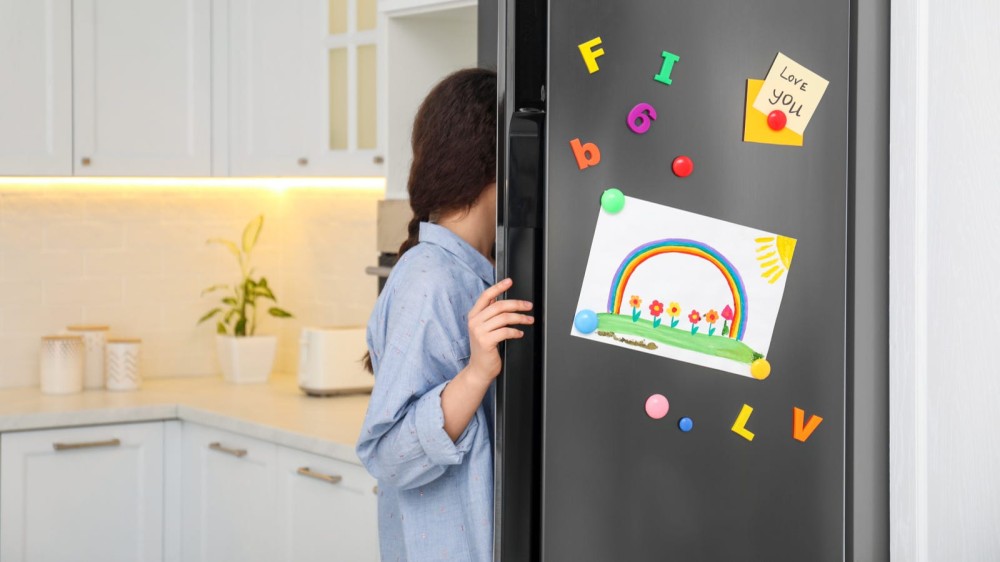 A woman opening a fridge door and grabbing something. 