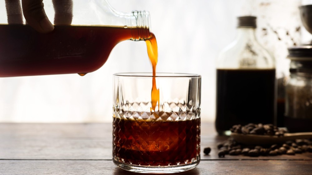 A bottle of cold brew coffee is poured into a glass.