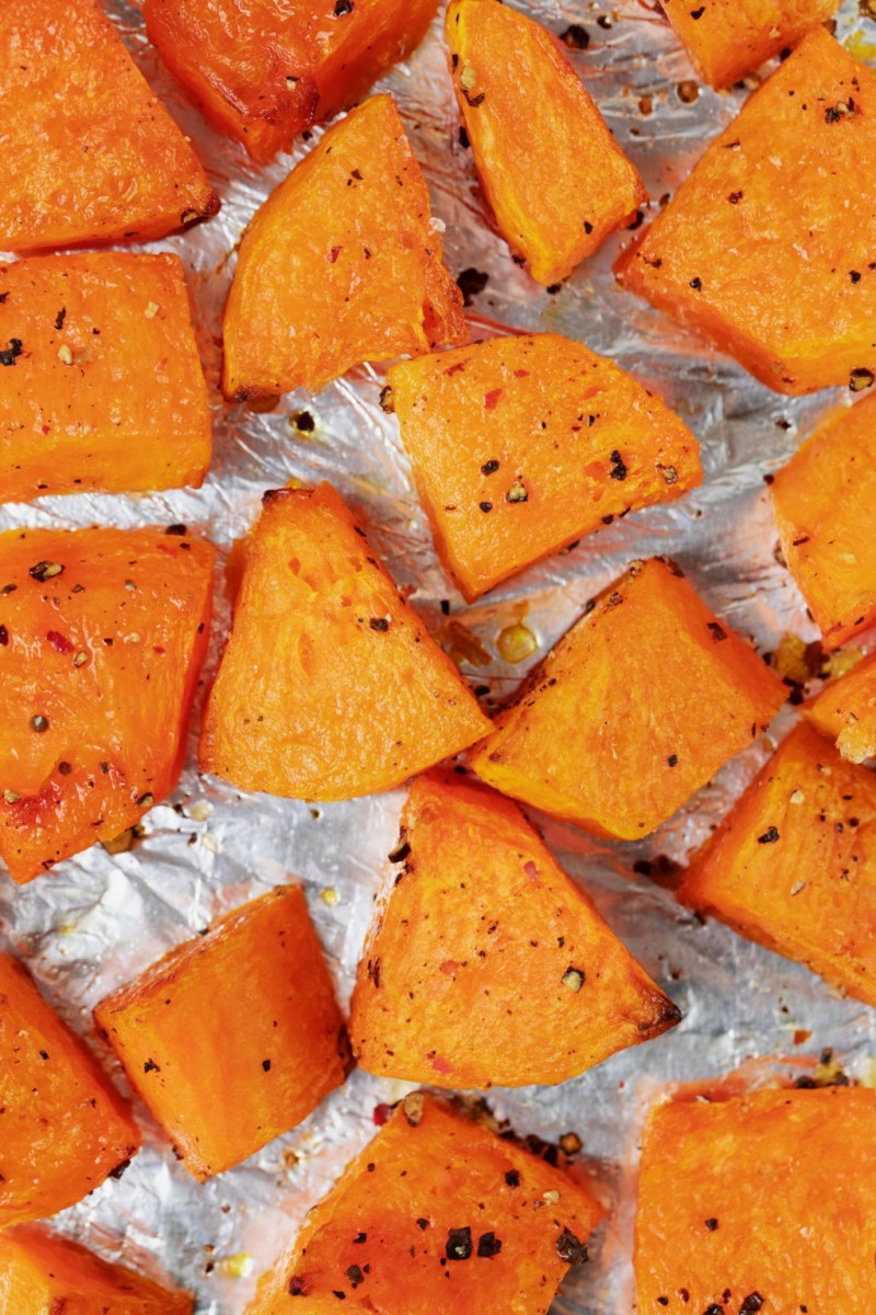 A foil lined baking sheet is covered in roasted pieces of winter squash.