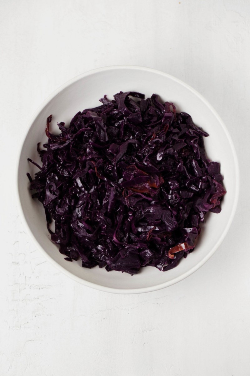 A white bowl has been filled with vegetables. It rests on a white surface.