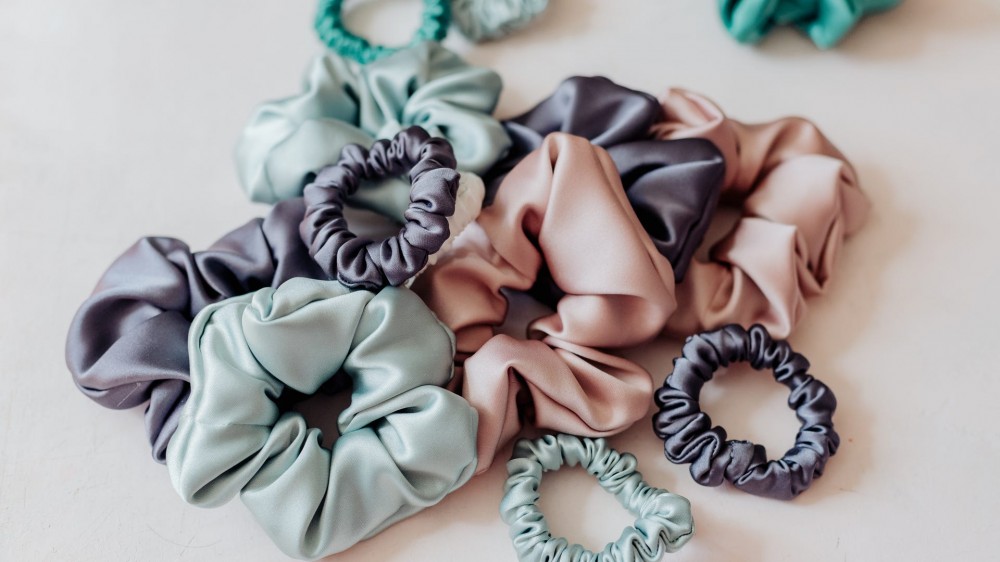 hair scrunchies of various sizes and colors in a pile on a white table.