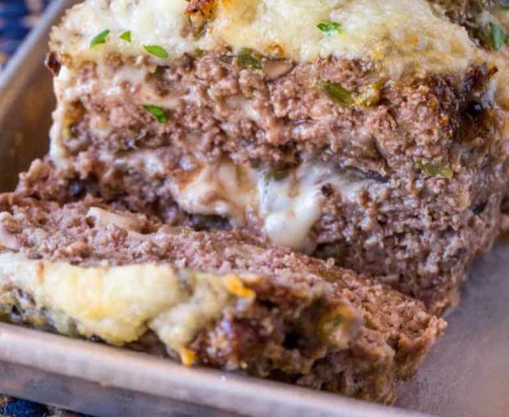 Philly cheese steak meatloaf that has just been sliced, with melted cheese.