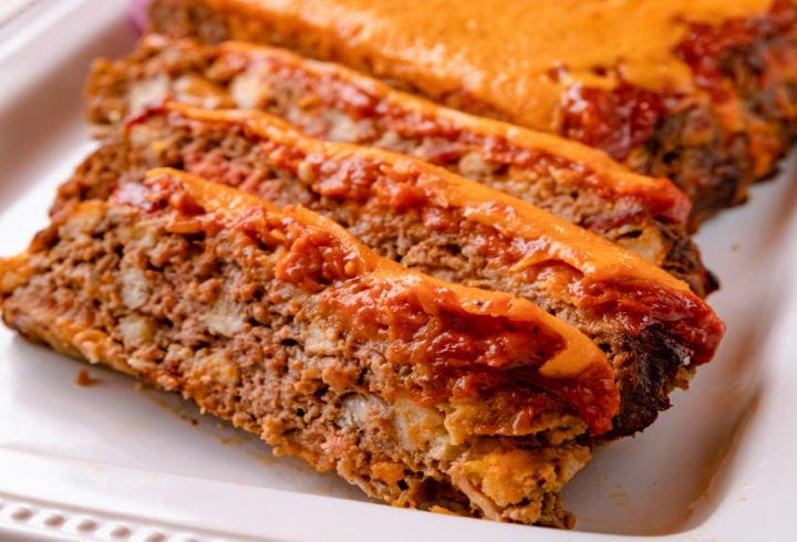 Sliced pieces of cheeseburger meatloaf topped with melted cheddar cheese.