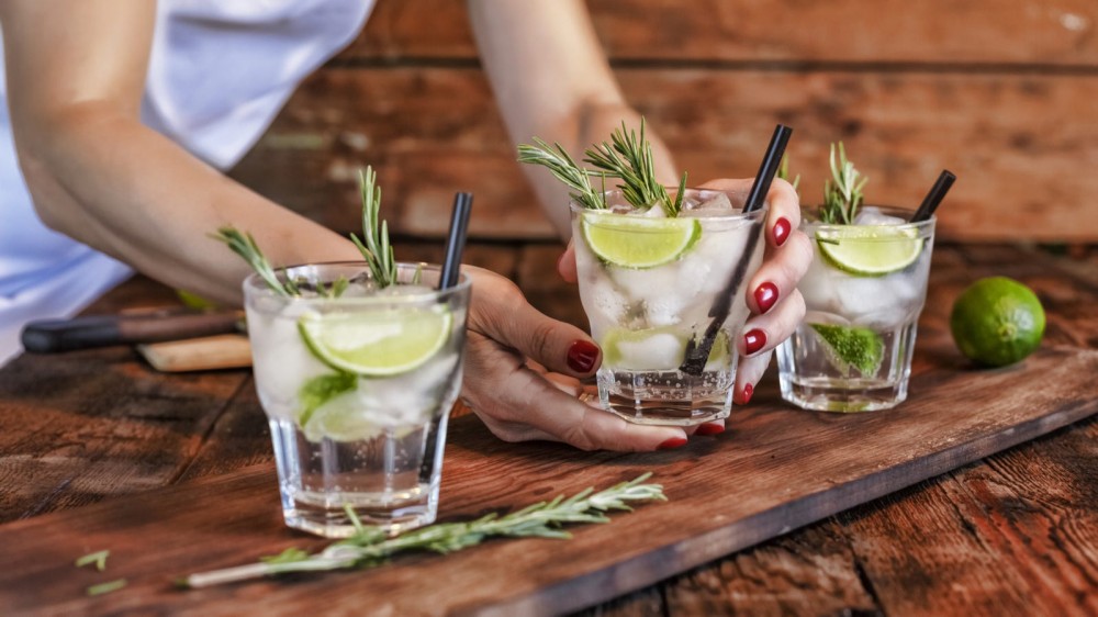 Some picking up a low carb cocktail made with vodka and soda water, enhanced with natural flavorings like fresh rosemary and a few lime wedges. 