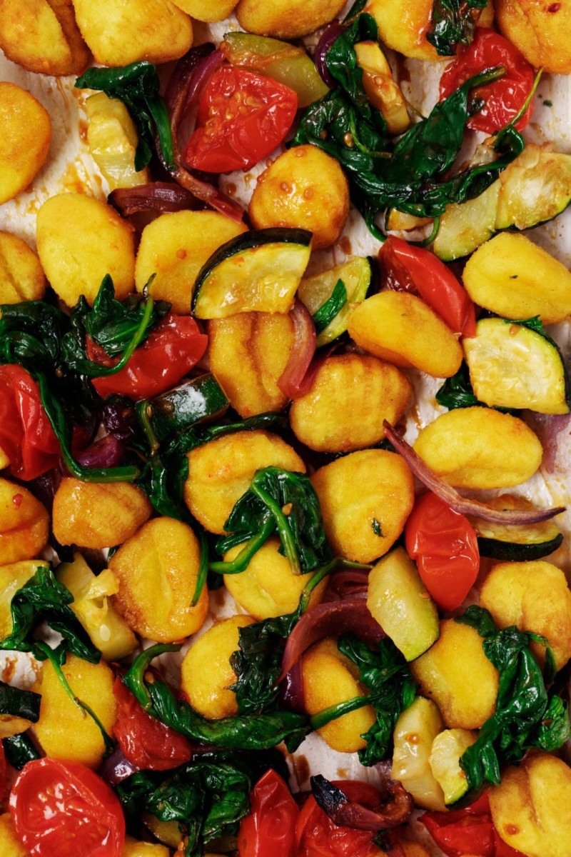 A baking dish has been topped with potato dumplings and roasted vegetables.