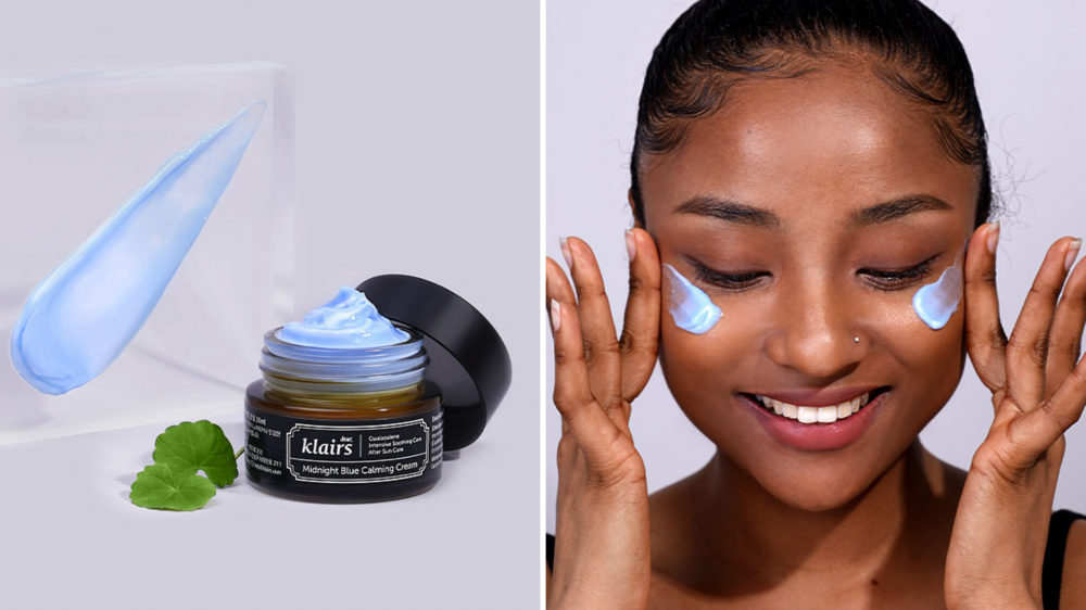 A tub of moisturizer sits on a counter, and a woman applies a blue cream to her face.