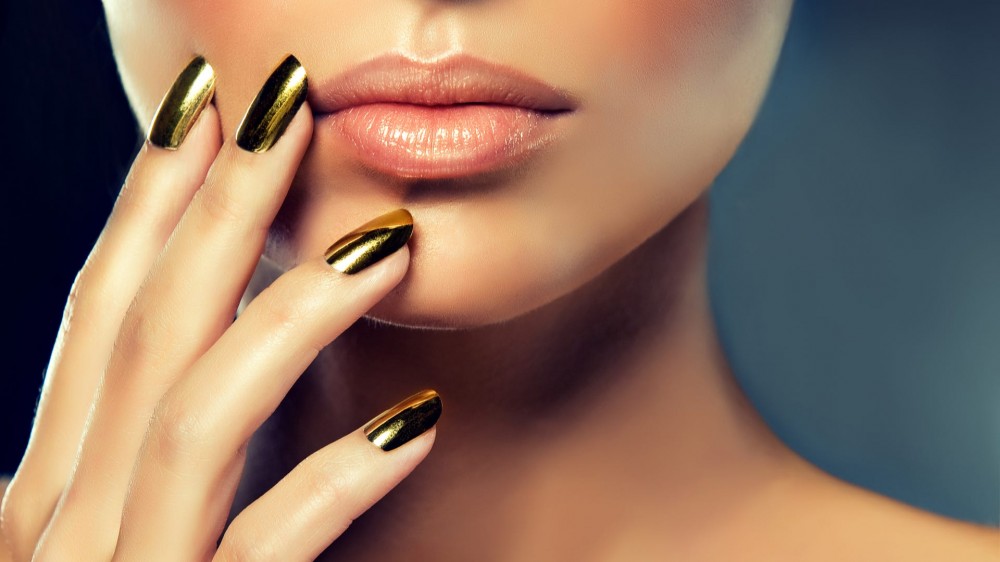 Beautiful girl with the golden makeup and gold metal nails.