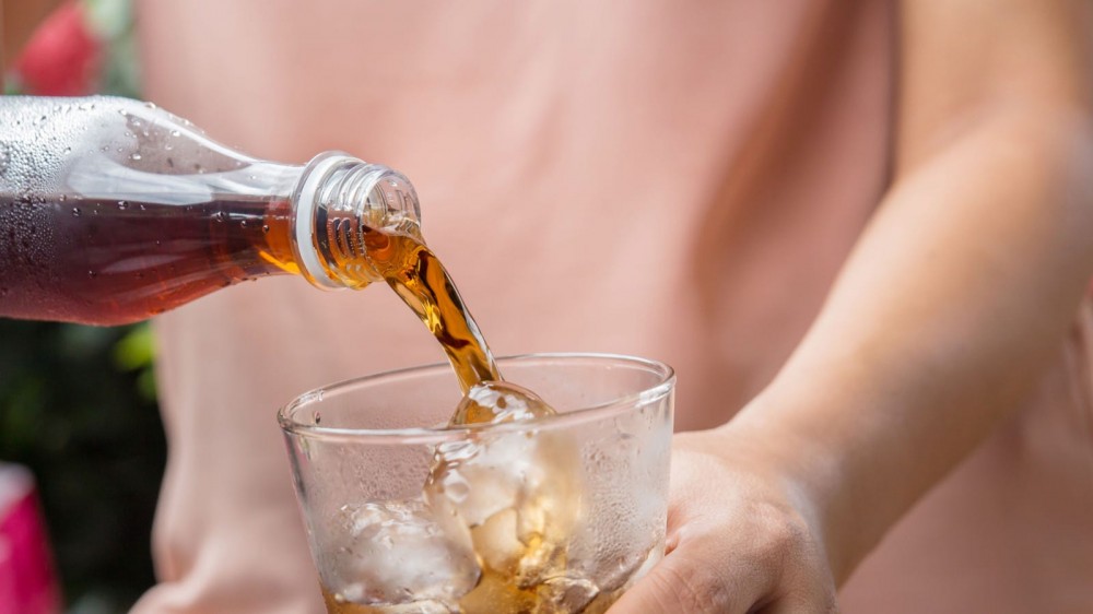 Woman pouring Coke into a glass.