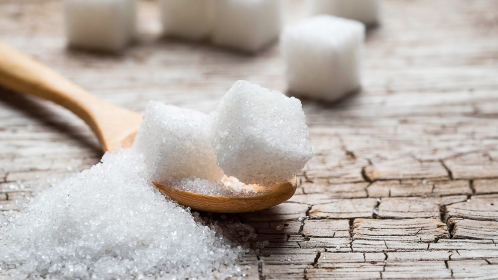 Sugar cubes on a wooden spoon.