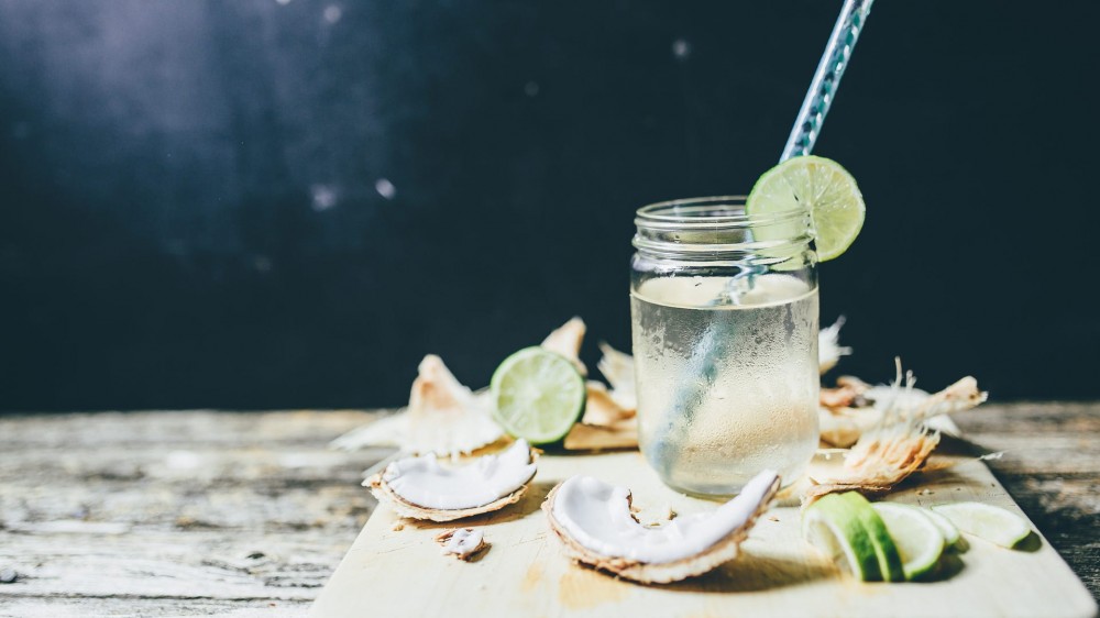 Coconut water inside of a mason jar next to cut-up coconut.