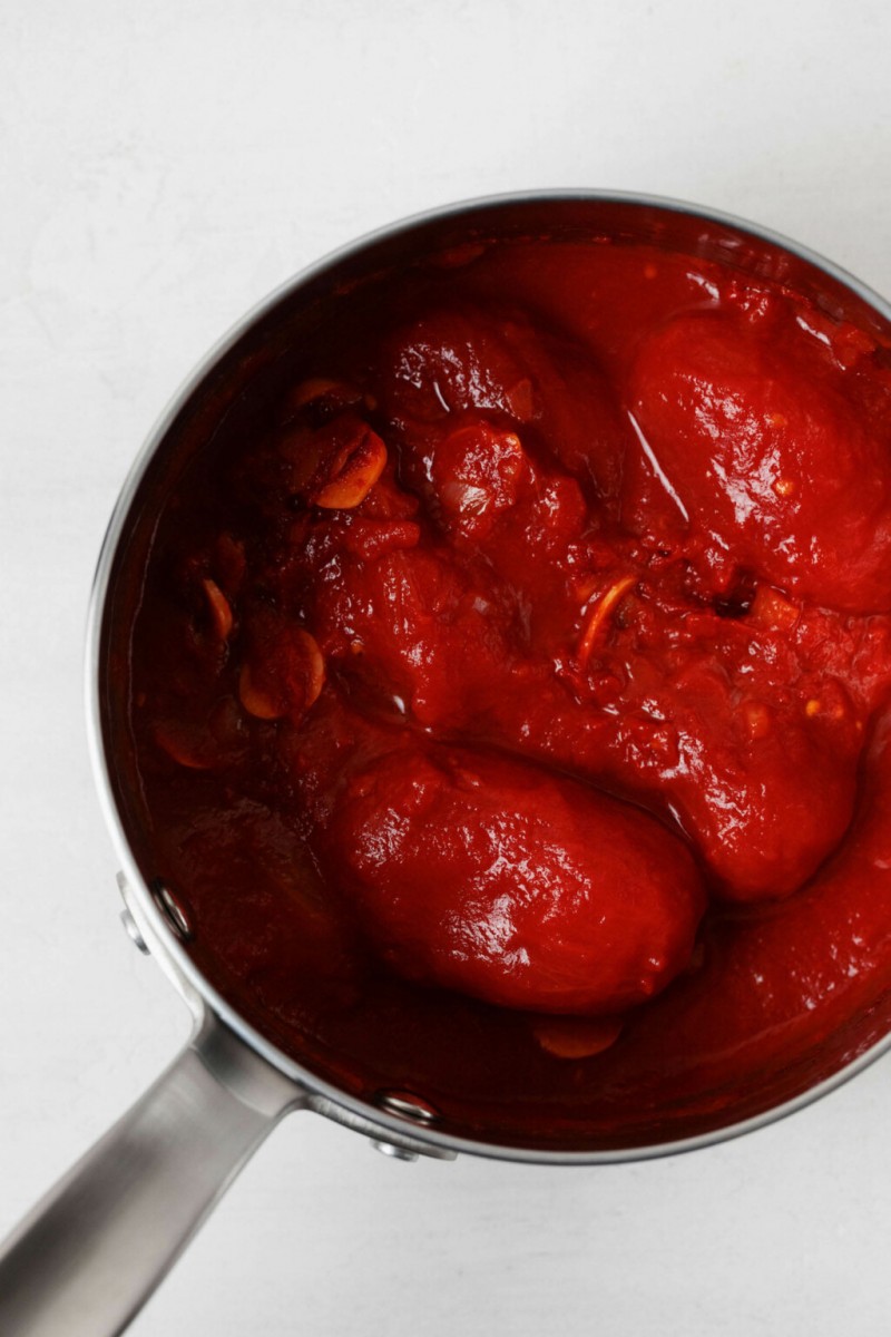 A sauce pot has been filled with roma tomatoes and garlic.