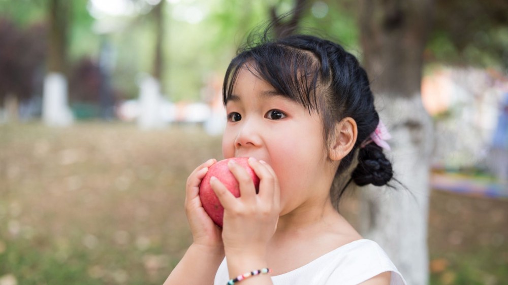 A girl snacks on an apple