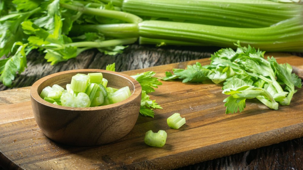 Celery and celery stalk on a wooden board.