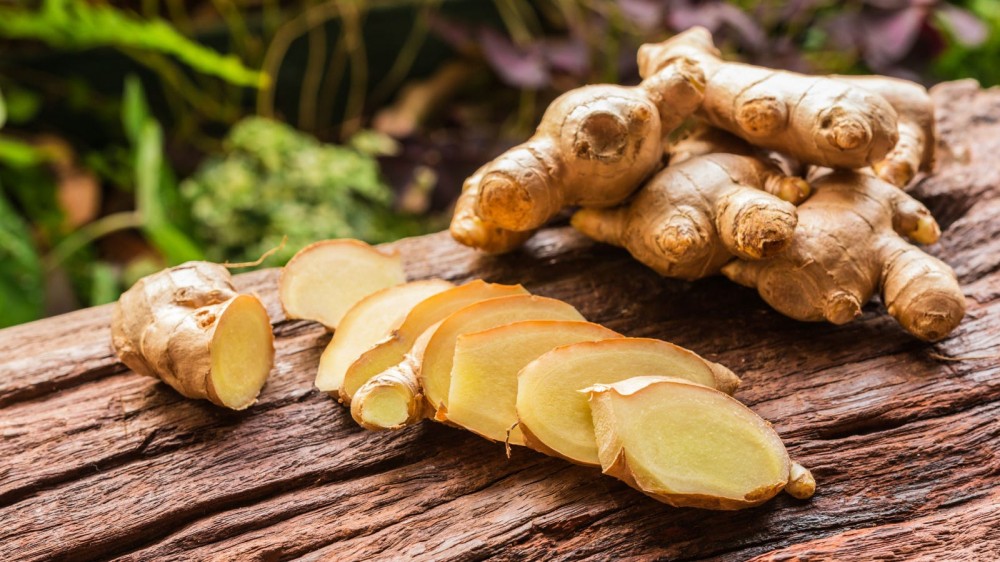 Sliced up ginger on a wooden board.