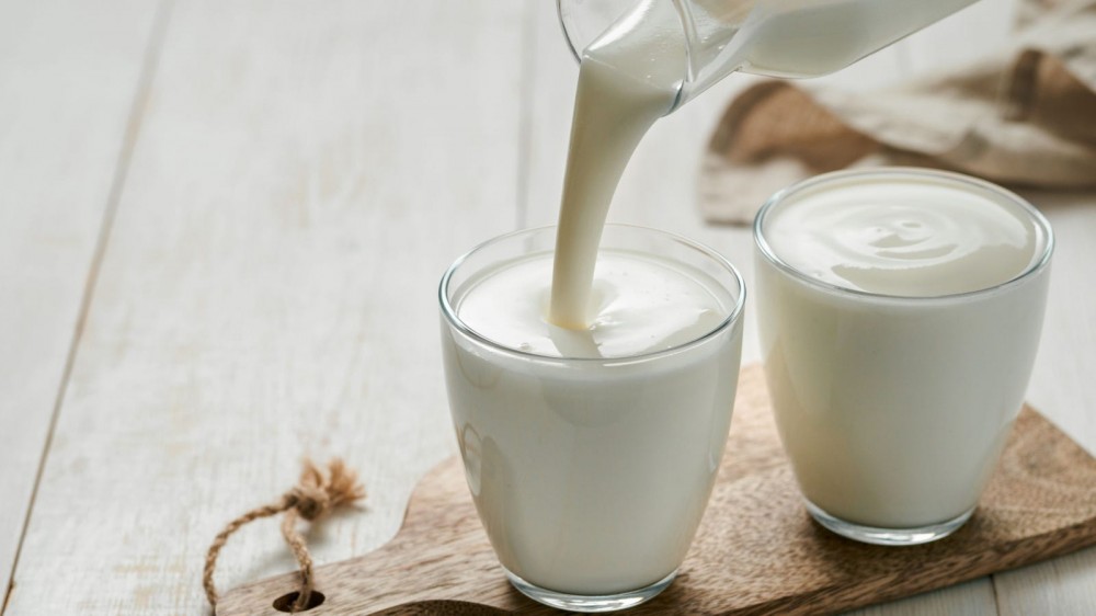 Yogurt being poured out of a glass pitcher.