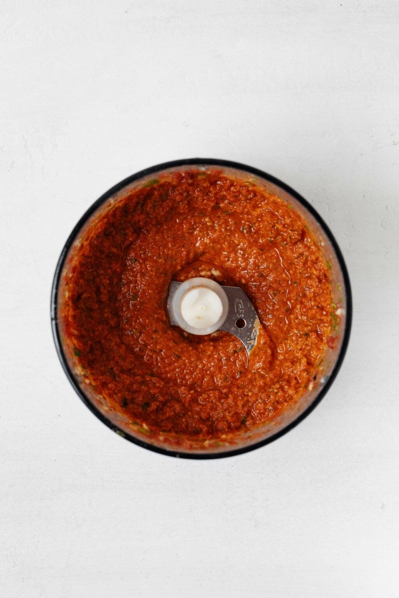 The bowl of a food processor is pictured from overhead. It is being used to make a sun-dried tomato pesto pasta.