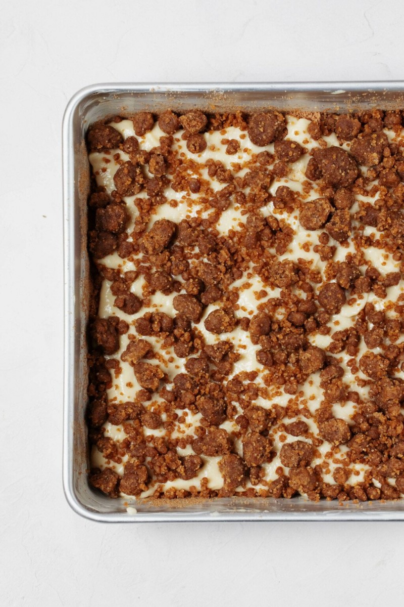 An overhead image of a square cake, which has not yet been baked. It's pictured in a baking dish with streusel topping.