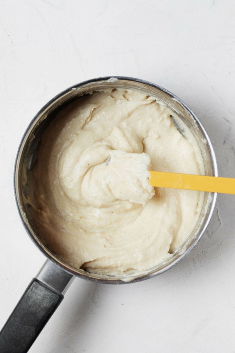 An overhead image of creamy vegan cashew "mozzarella"-style cheese sauce. The sauce is warmed in a saucepan before use.