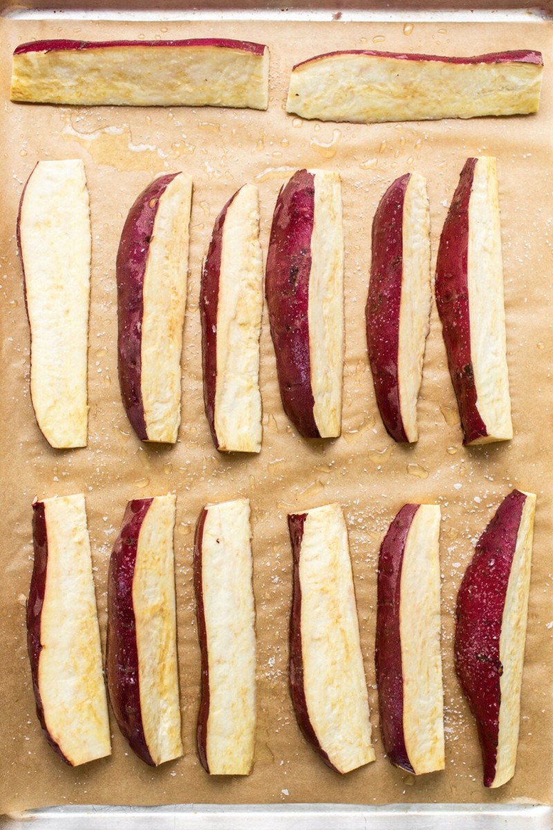 Wedges of Japanese sweet potato are arranged on a brown parchment sheet.